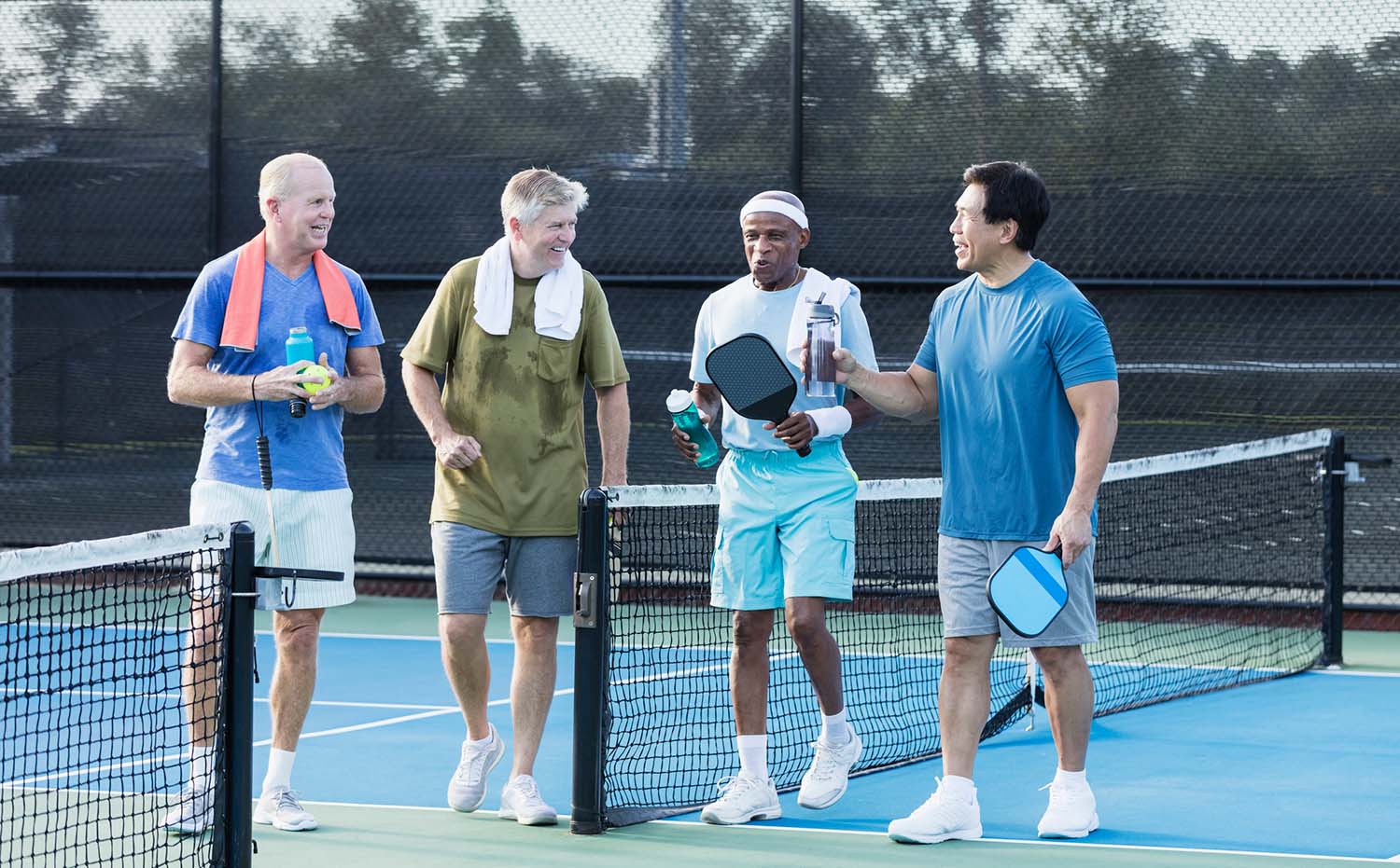 Active Senior Men Playing Pickleball on Outdoor Court